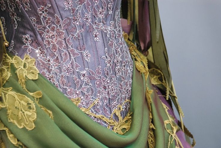 close up of a garment with purple lace and green fabric featuring yellow floral embroidery