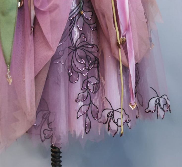 Close up of sheer fabric with embroidered floral patterns and hanging ribbons
