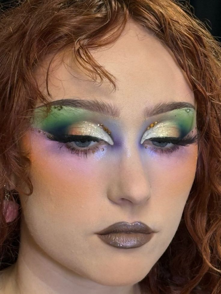 Person with wavy hair wearing vibrant make up, long lashes and rhinestones near the eyes