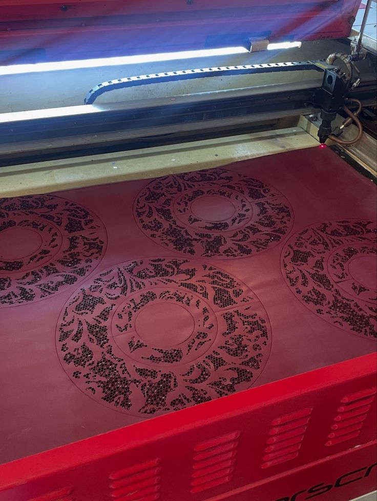 Laser engraving machine etching circular floral patterns on a thin latex surface