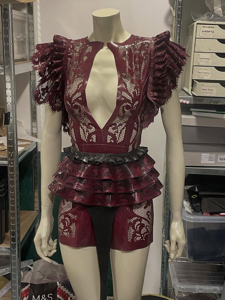 Mannequin wearing a burgundy lace dress with deep front cutout, ruffled shoulders and tiered ruffle skirt