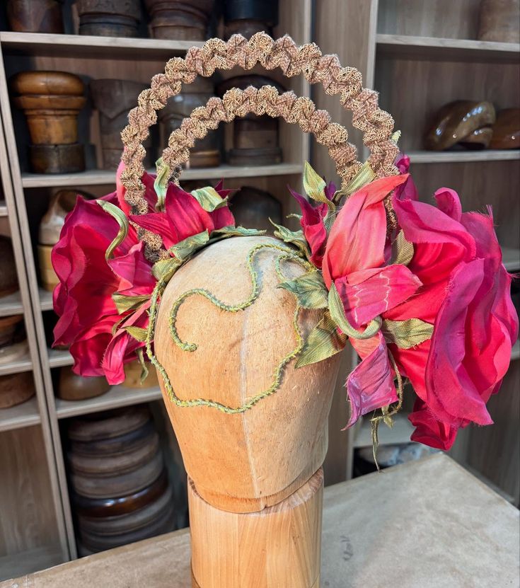 Headband with large fabric flowers and braided bands on a wooden mannequin head