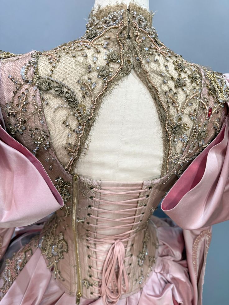 Back view of a pink corset dress with lace-up closure and intricate bead and sequin embroidery on sheer fabric